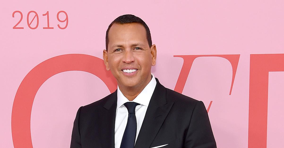 Alex Rodriguez smiles in front of a pink backdrop.