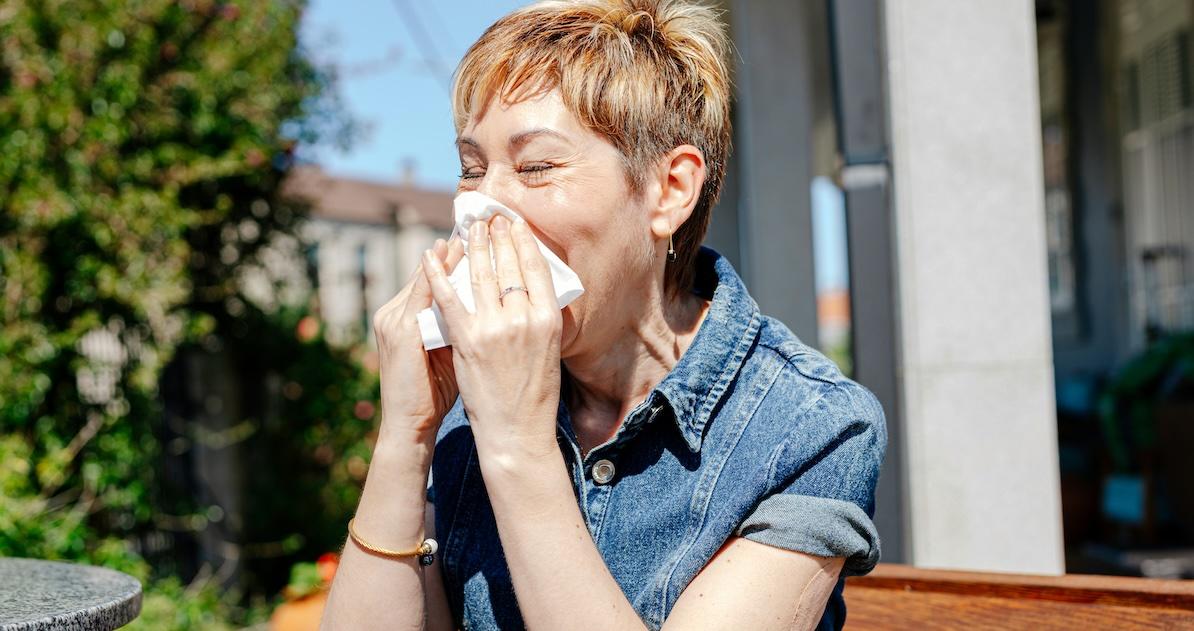 woman sneezing into tissue