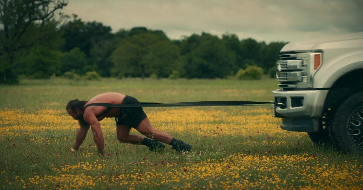 Brian Johnson uses a strap to pull a truck behind him