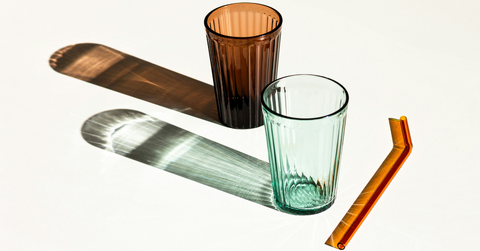 Two glasses sit next to a straw