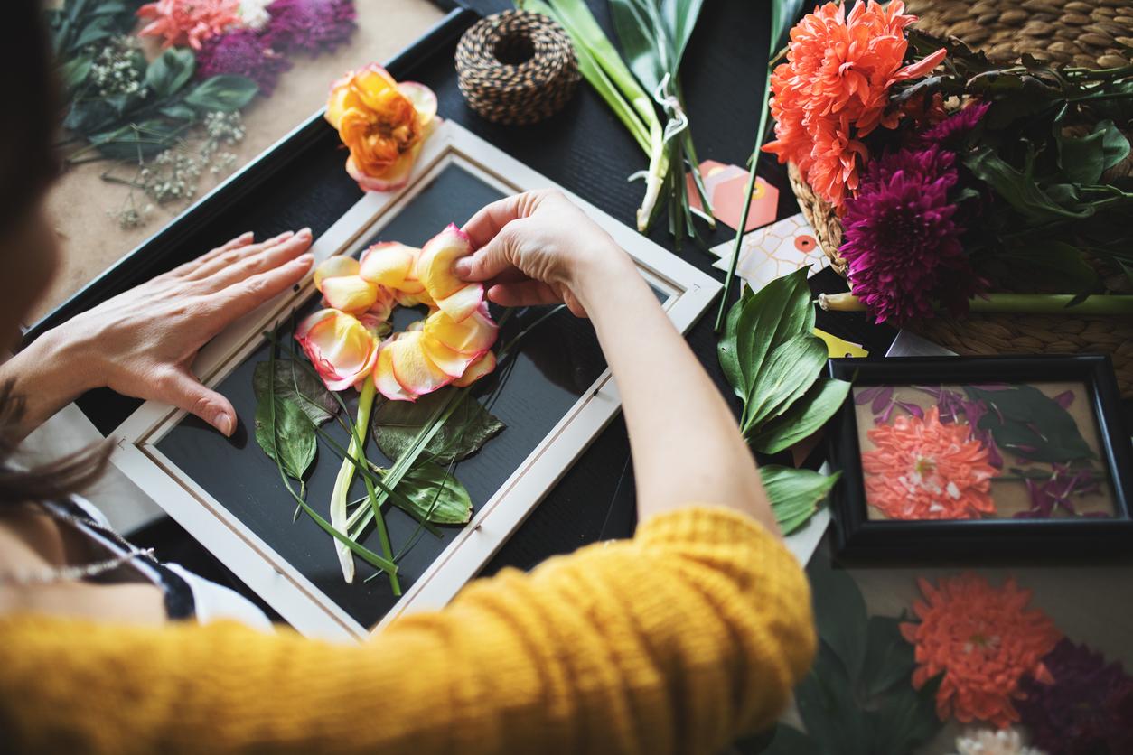 Person arranging pressed flowers on a glass frame