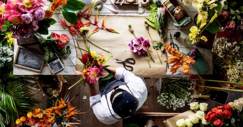 Photo of overhead view of florist cutting stems and hand-making bouquets