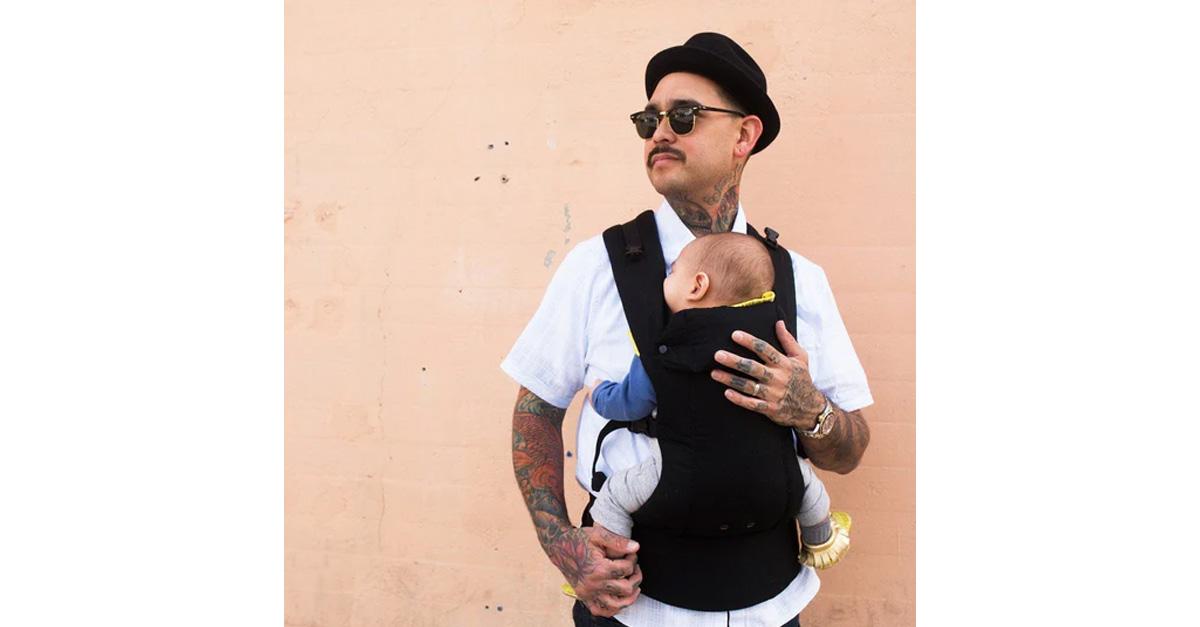 Dad carrying baby in black baby carrier.