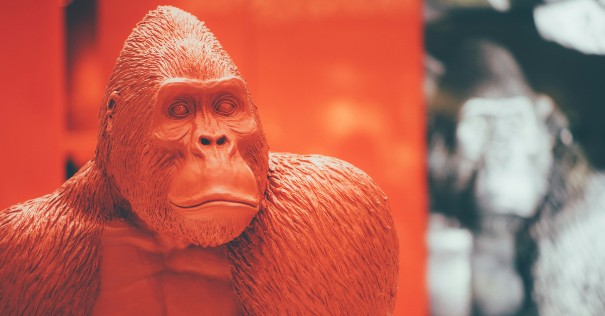 A statue of a gorilla sits in front of a black and white photo