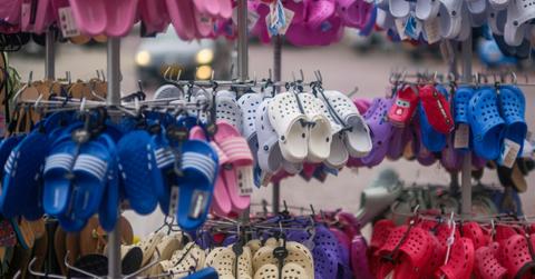 Several sizes and colors of Crocs shoes hang on a wall in a store