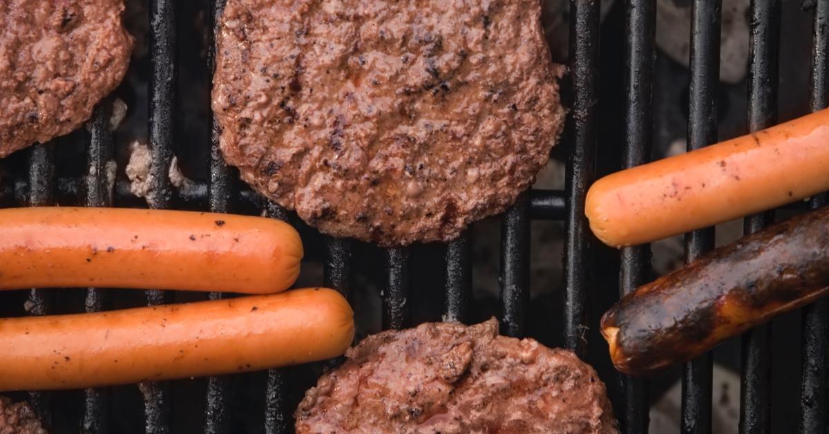 Photograph of hamburgers and hot dogs on a grill. 