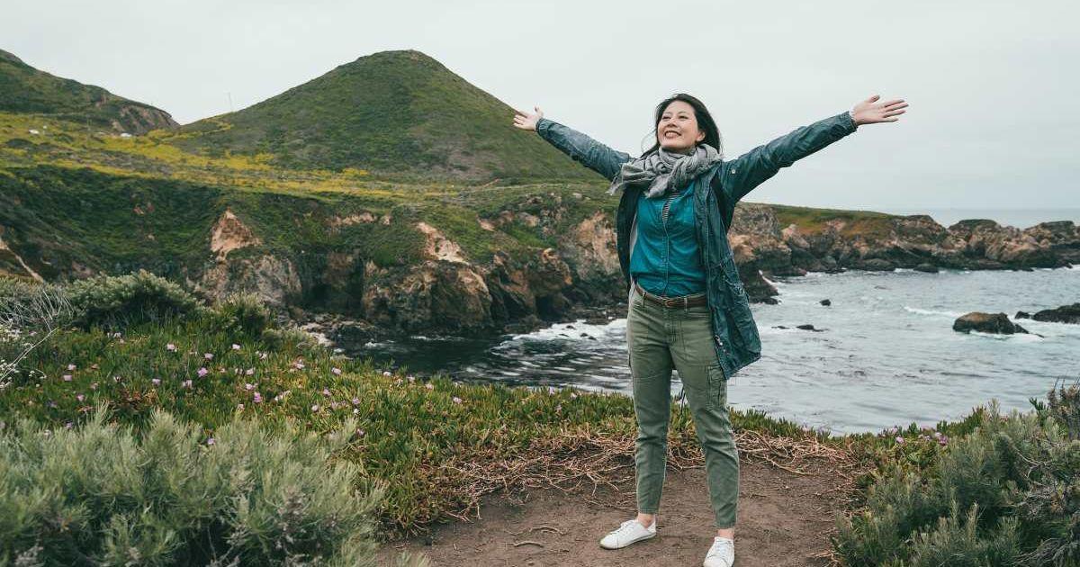 A woman visitor spreads her arms wide while visiting a state park in California (Representative Cover Image Source: Getty Images | PrimAgeFactory)