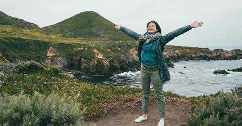 A woman visitor spreads her arms wide while visiting a state park in California (Representative Cover Image Source: Getty Images | PrimAgeFactory)