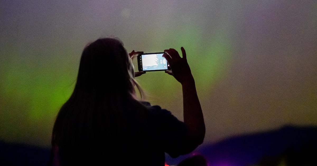  A woman photographs the Northern Lights at Chanticleer Point Lookout on the Columbia River Gorge in the early morning hours of May 11, 2024 in Latourell, Ore.