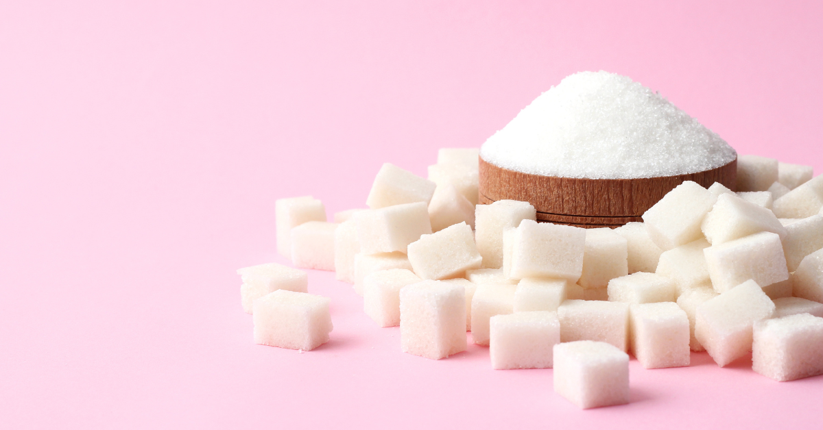 Closeup of refined sugar and sugar cubes with a pink background