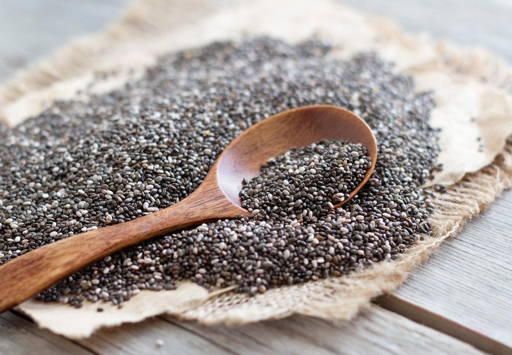 A wooden spoon on top of a bed of chia seeds.