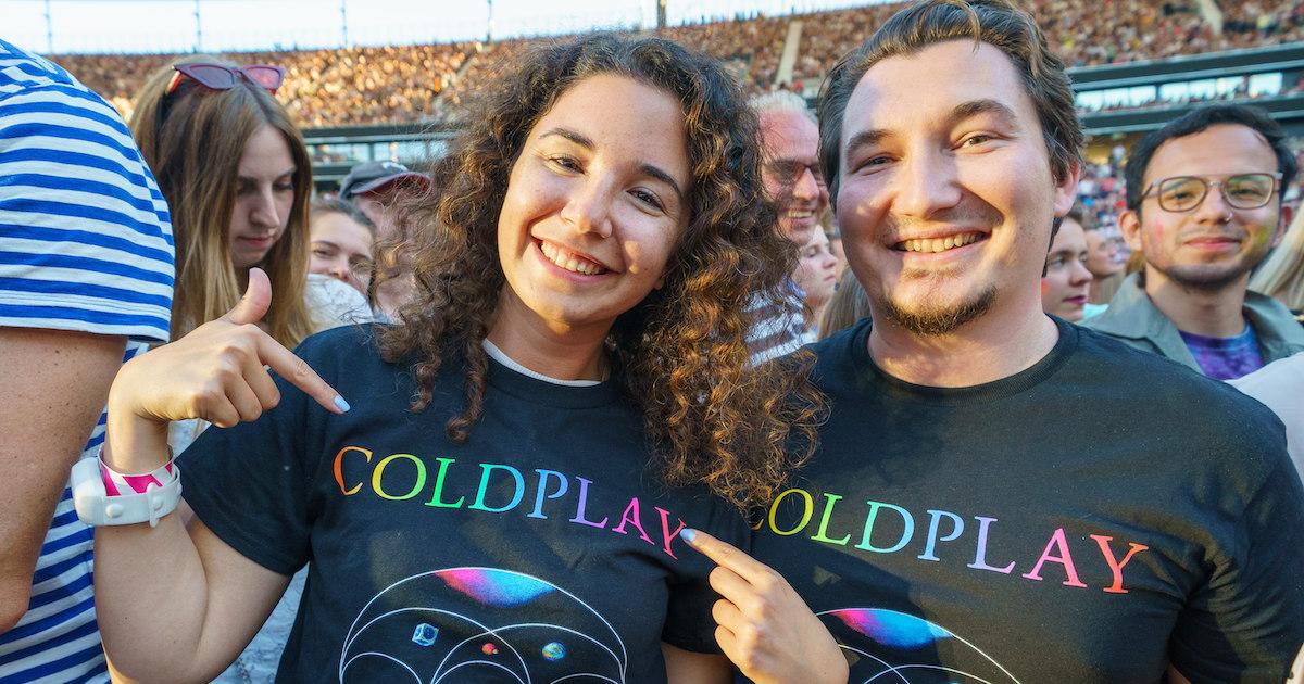 Two fans point to their black Coldplay T-shirts on July 2, 2022 in Hessen, Frankfurt.