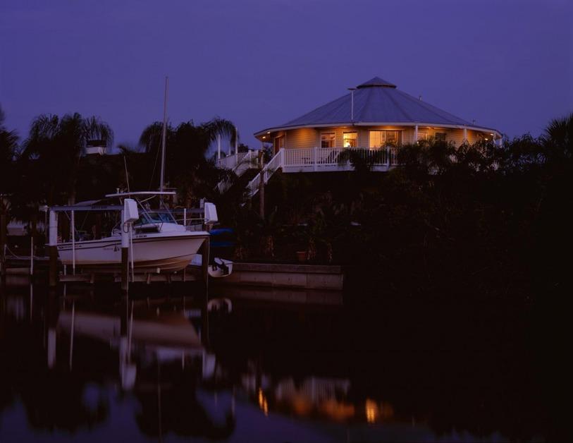 A Deltec home photographed in the evening on the waterfront with a boat at the dock. 