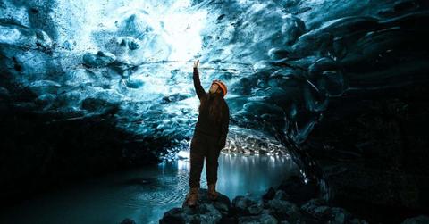 A researcher standing inside an ice cave with a lake inside it. (Representative Cover Image Source: Pexels | Priyanka Varlani)