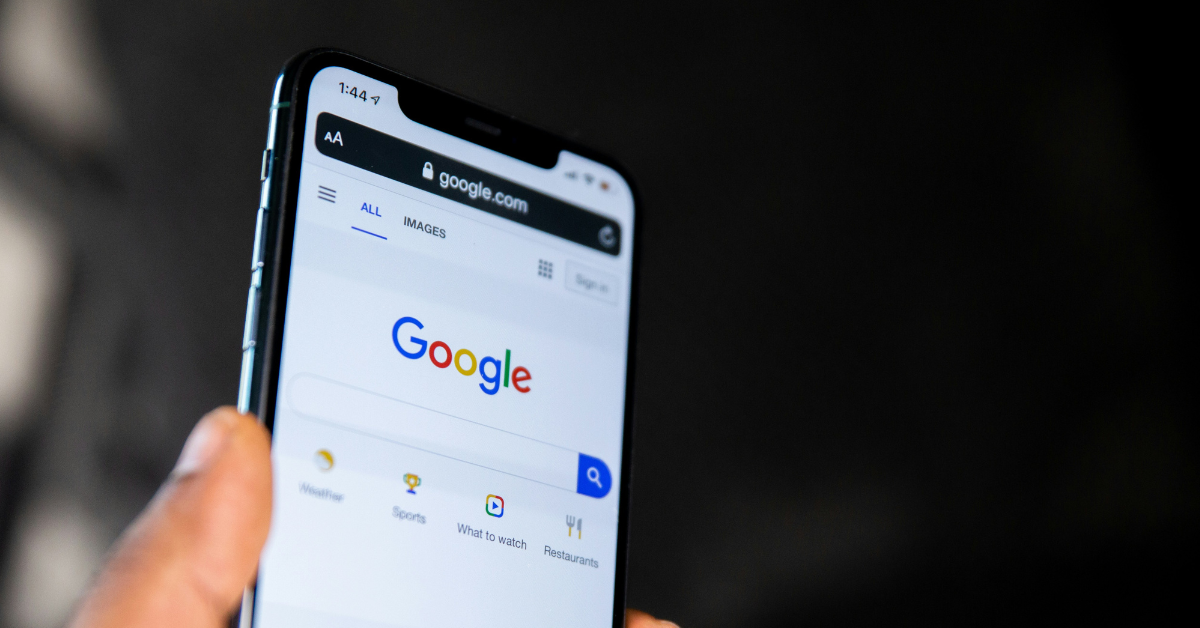 A person holds a phone screen showing a Google search prompt
