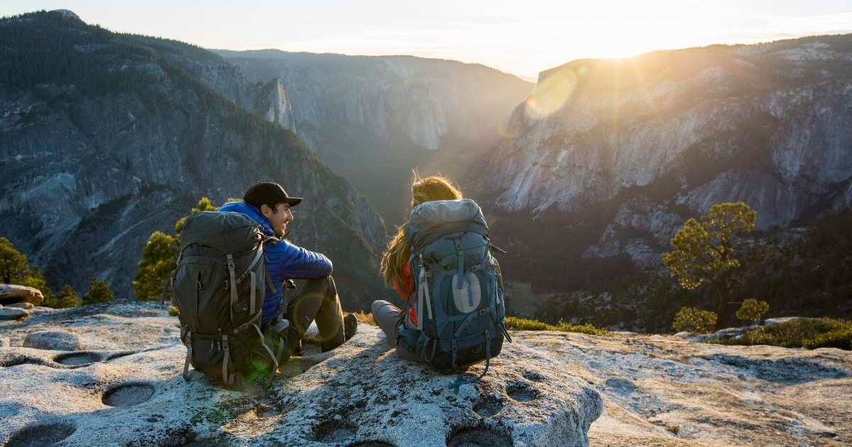Picture of two people sitting on a ledge in Yosemite Valley. (Representative Cover Image Source: Getty Images | Jordan Siemens)