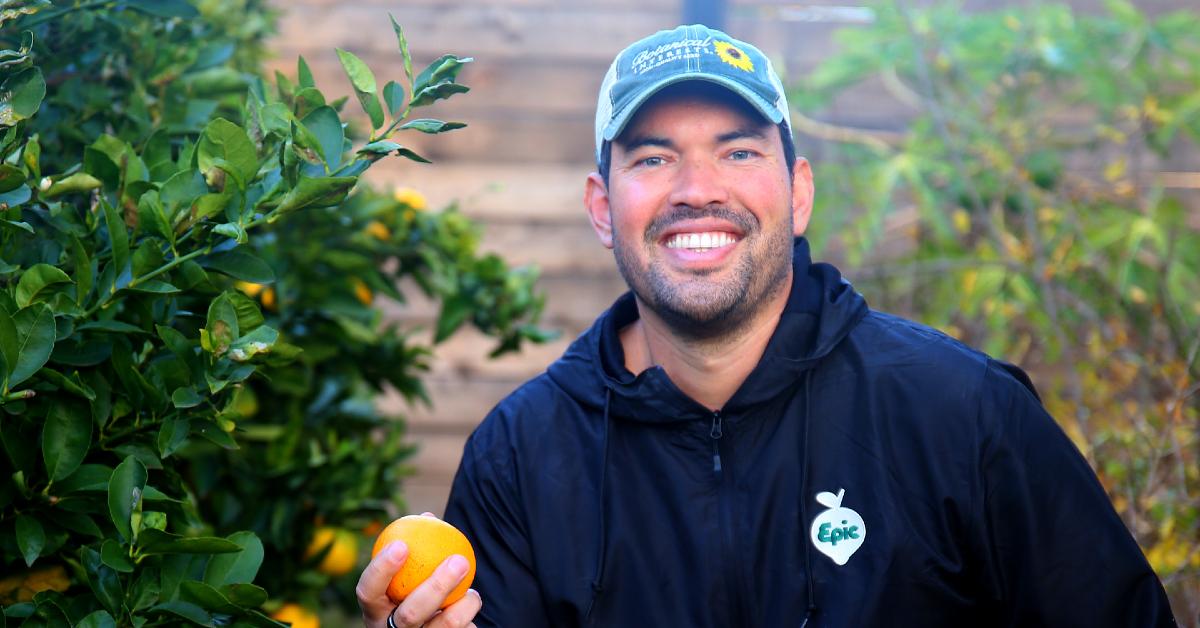 Headshot of Epic Gardening CEO and founder Kevin Espiritu holding an orange at his urban homestead