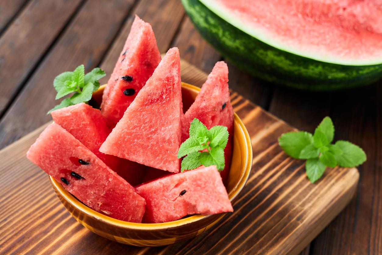 Watermelon sliced into triangles in a bowl on a cutting board.