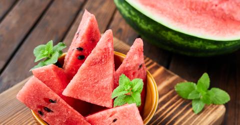 Watermelon sliced into triangles in a bowl on a cutting board.