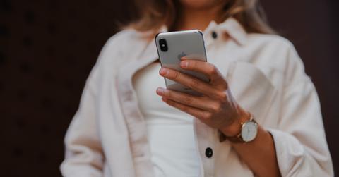 woman in cream shirt looking at smartphone