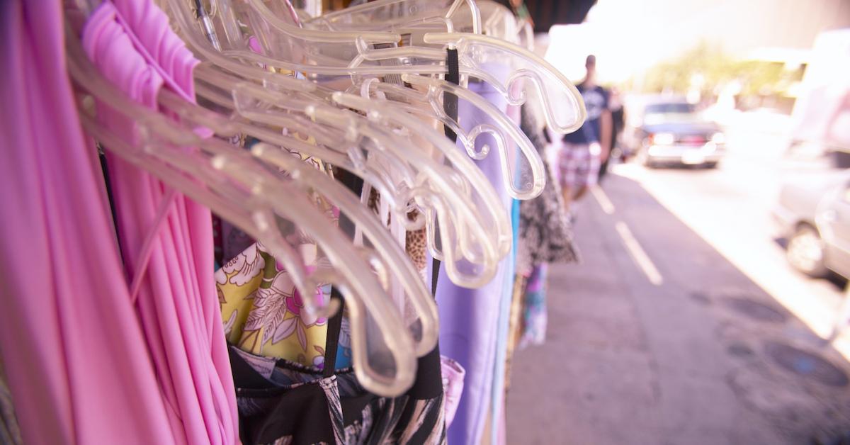 Photograph of dresses hanging from plastic hangers. 