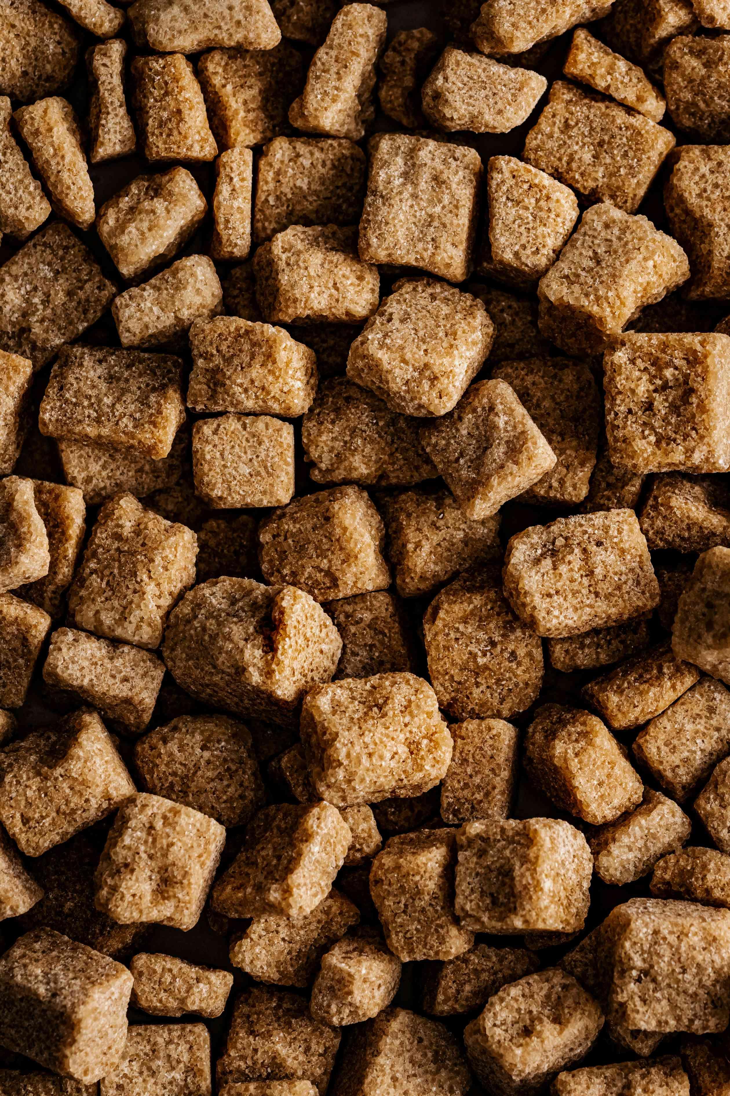 Brown sugar cubes are pictured up-close and stacked atop one another.