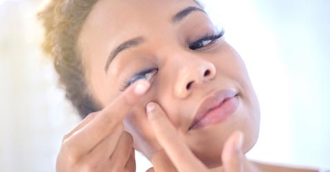 A woman puts a contact lens in her eye