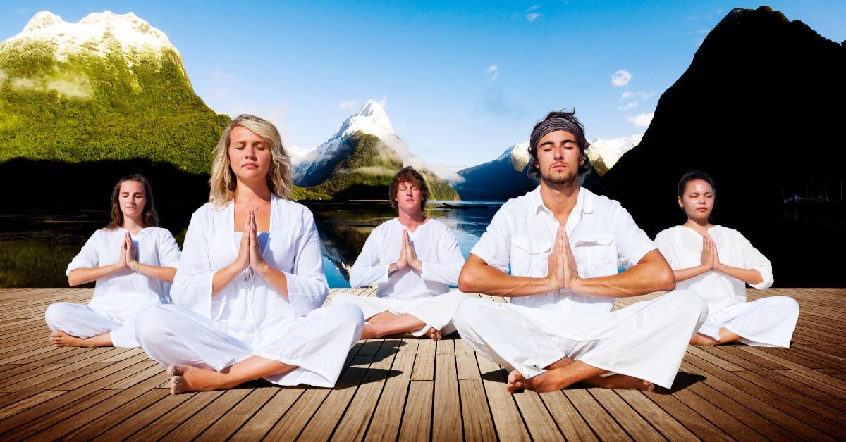 People meditating while wearing comfortable clothes and sitting on a dock