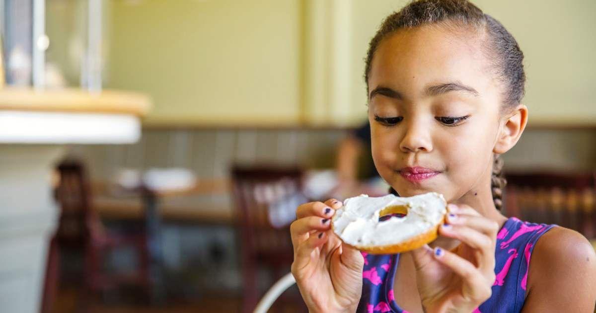 A little girl is eating a bagel in a cafe. (Representative Cover Image Source: Getty Images | Inti St Clair) 