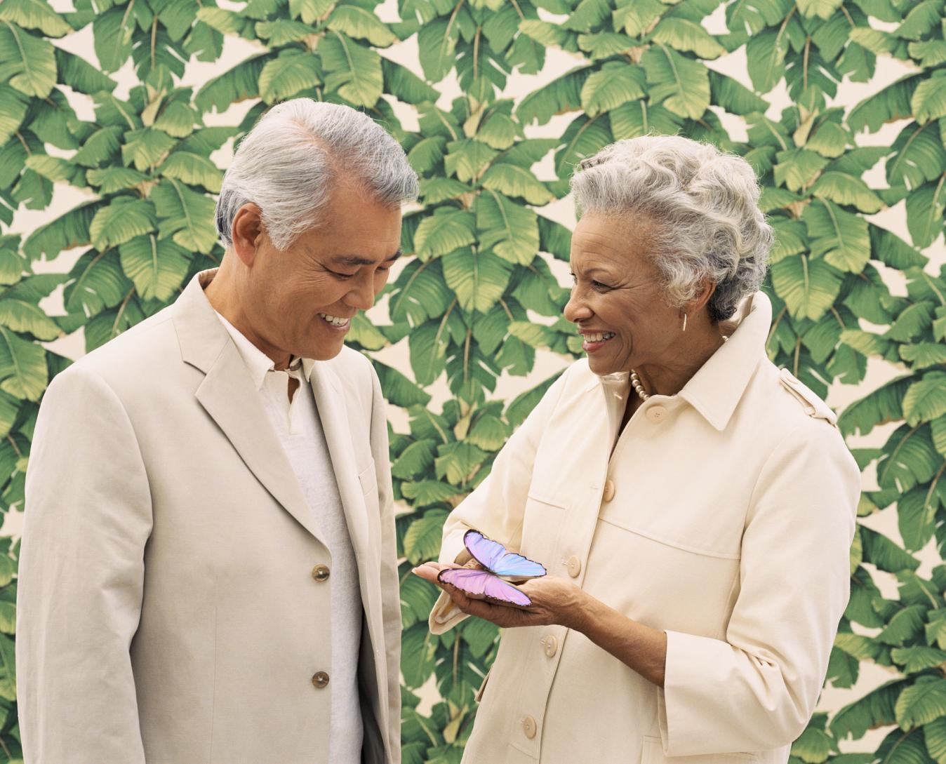 A married couple smiles upon a colorful butterfly.