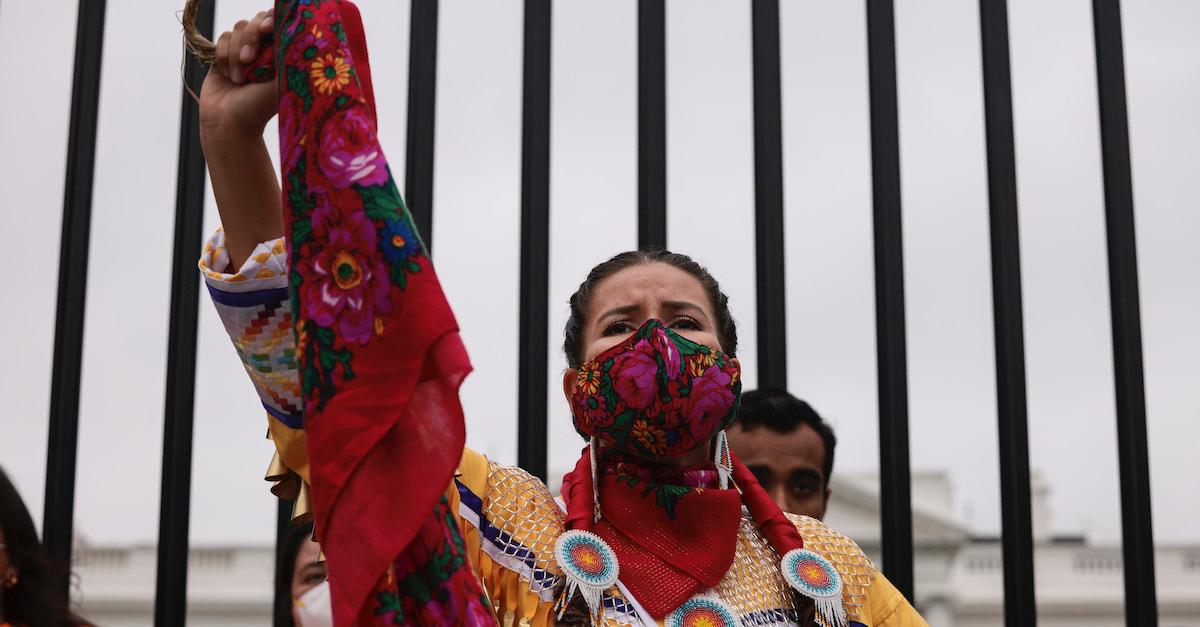 Native American woman holds up a scarf at a protest