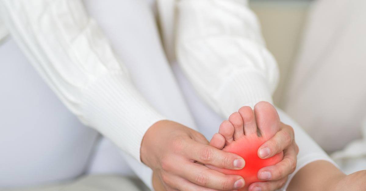 A woman massaging her foot on a bed