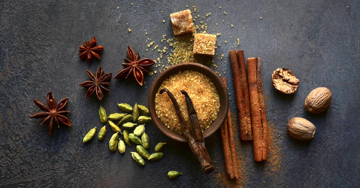 A beautiful array of chai spice ingredients on a dark grey slate surface