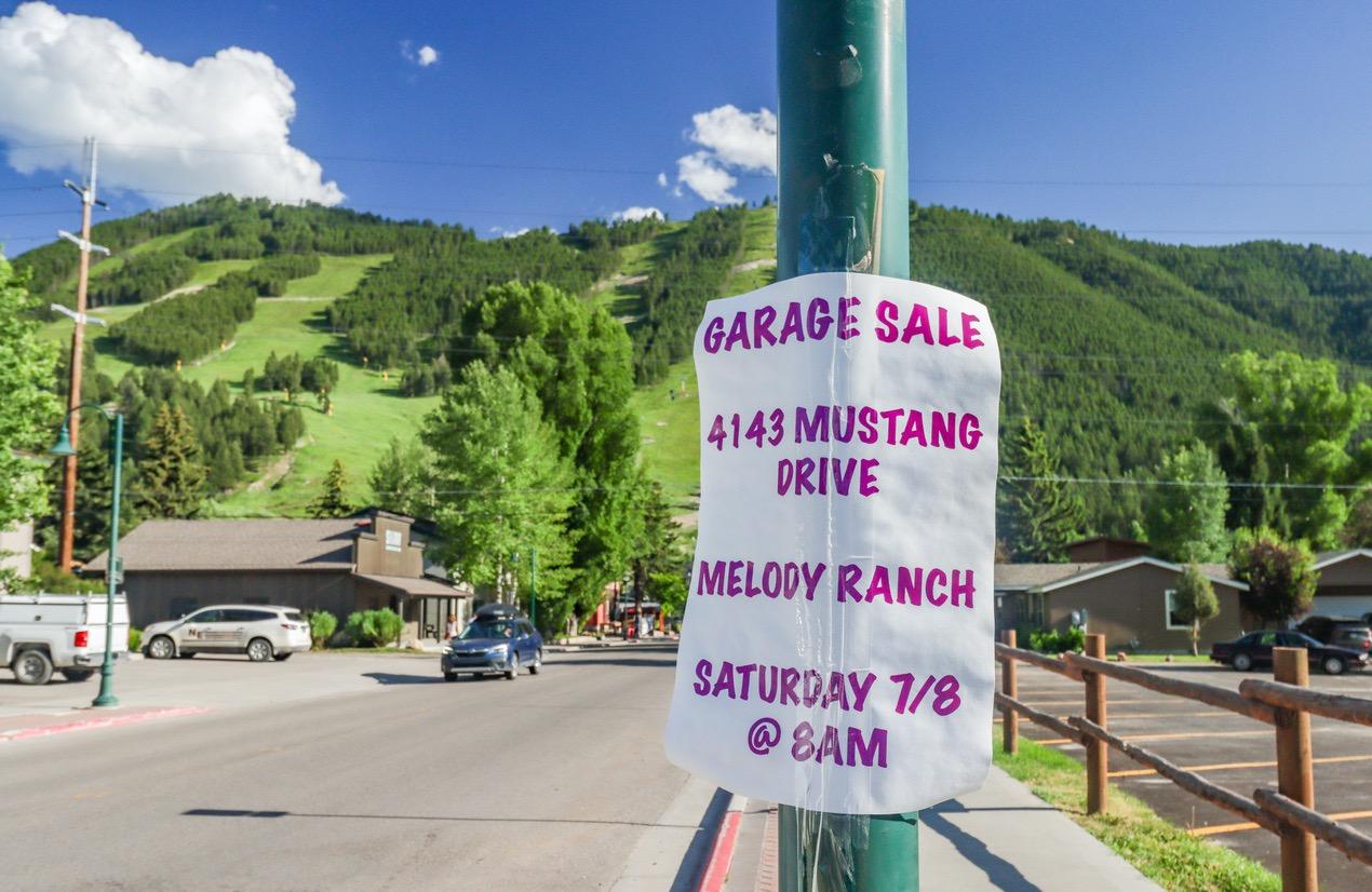 Garage sale poster with relevant information on a post in a town.