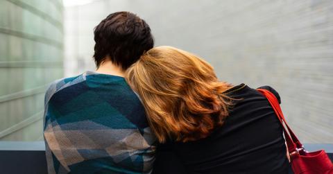 A woman lays her head on the shoulder of a short haired person