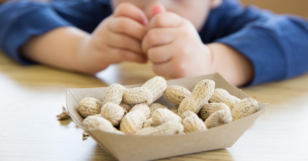 Child sitting at a table across from peanuts