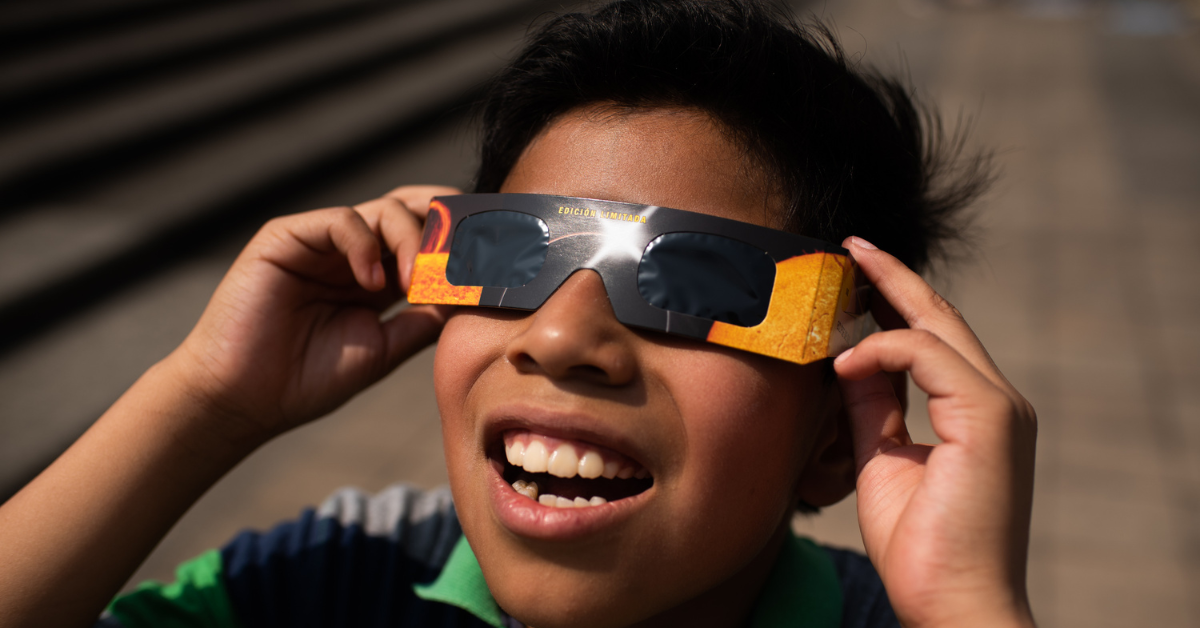 A young boy wears solar eclipse glasses while viewing the April 2024 eclipse