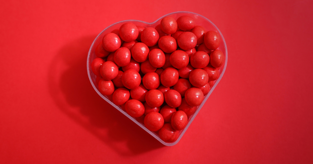 A heart shaped candy dish holds red candies