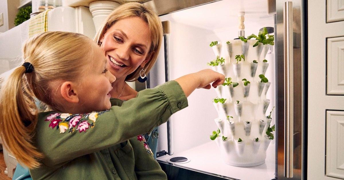 A blonde mother and young daughter smile as they look at an Anu hydroponic planter