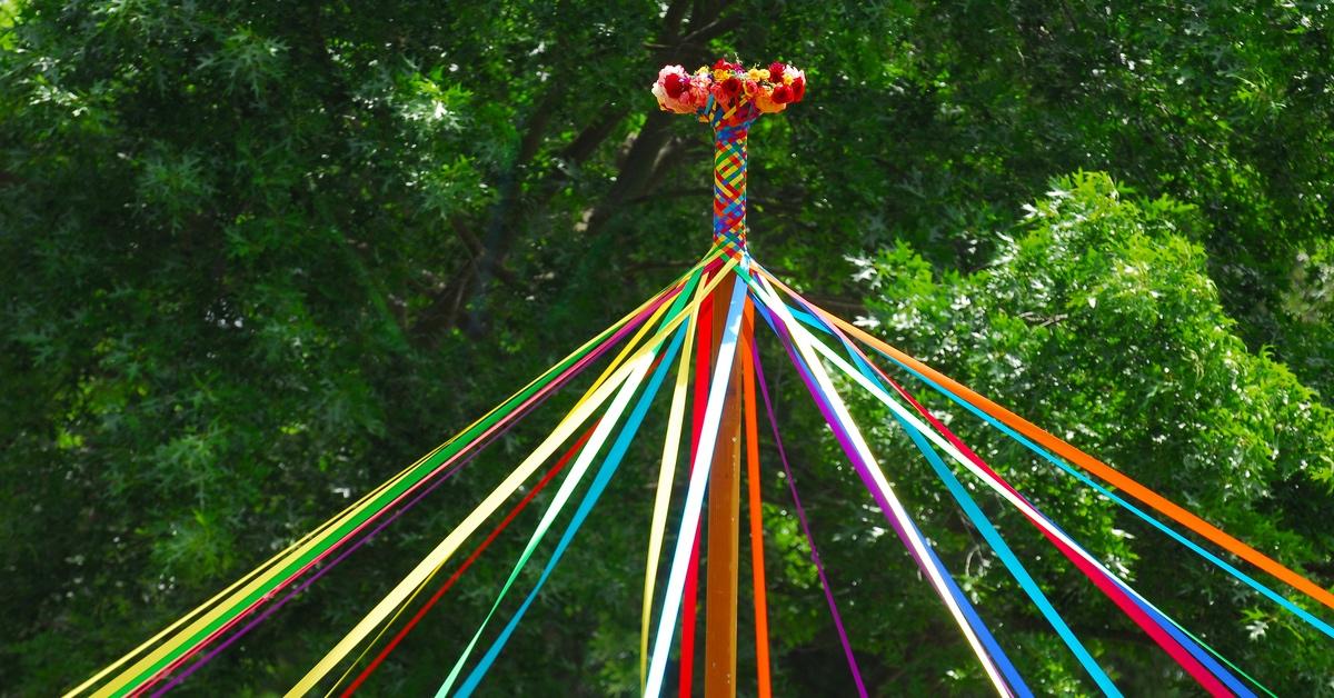 Multicolored May pole on May Day outdoors with a forest background. 