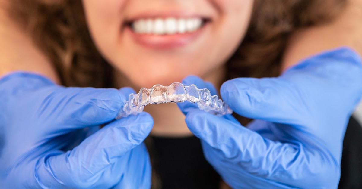 Orthodontist doctor putting silicone invisible transparent braces on woman