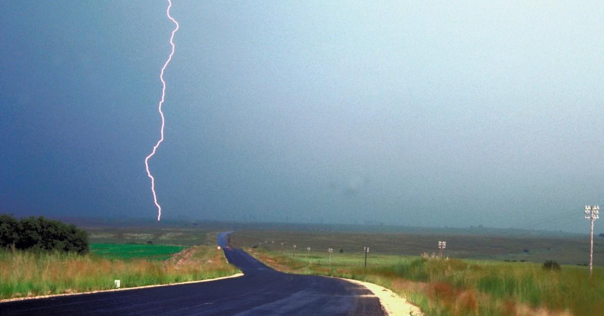 A bolt of lightning touches down next to a road