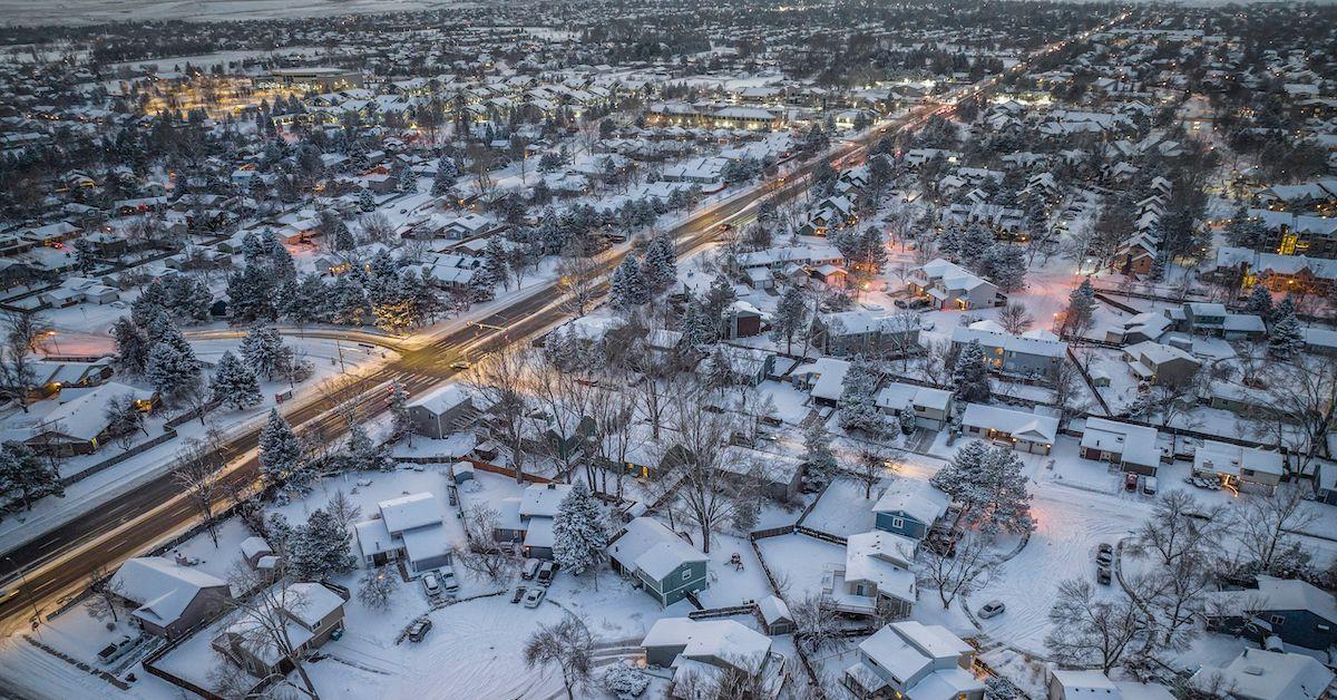 Aerial shot of neighborhood covered in snow, in evening