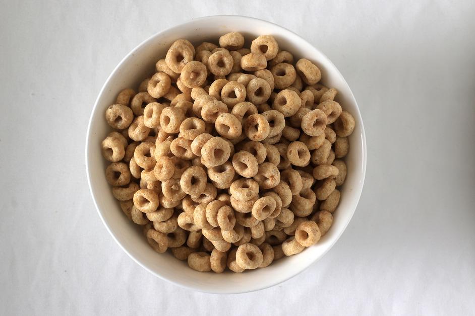 A overhead photo of a white bowl of plain Cheerios cereal.