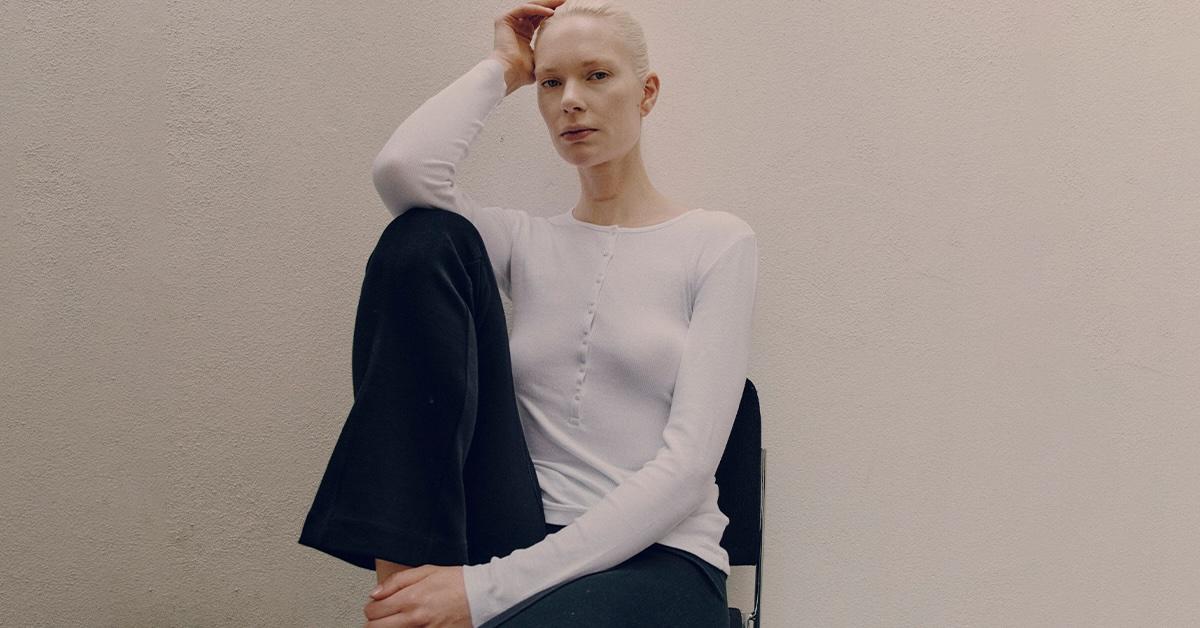 Bald model in white shirt and black pants by Ninety Percent