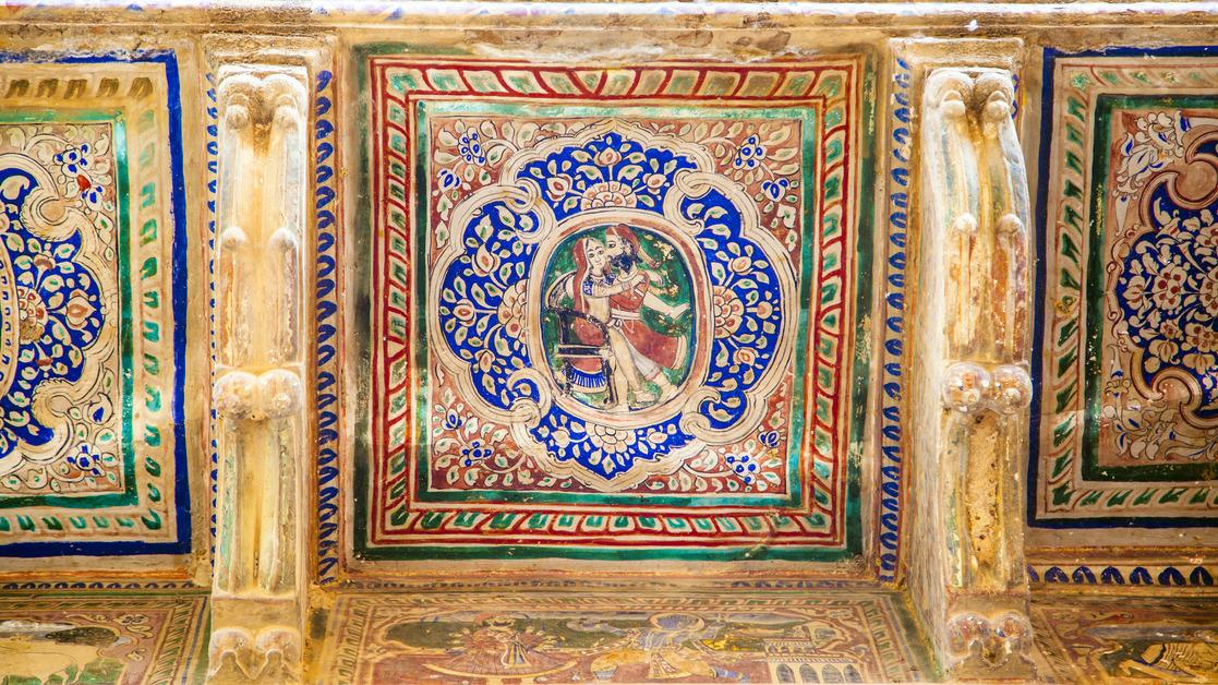 A view of a gold ceiling with colorful depicting deities practicing tantra. 