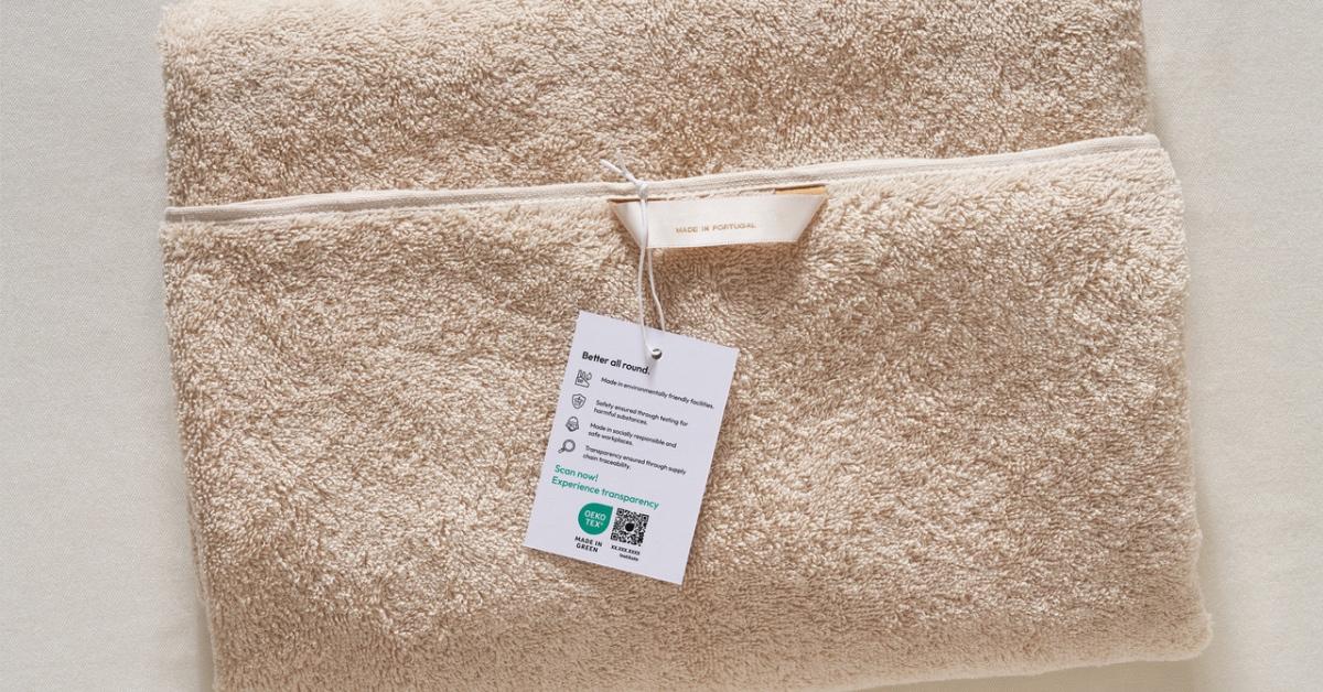 Close-up photograph of a tan towel with the OEKO-TEX Made in Green label and QR code on it. 