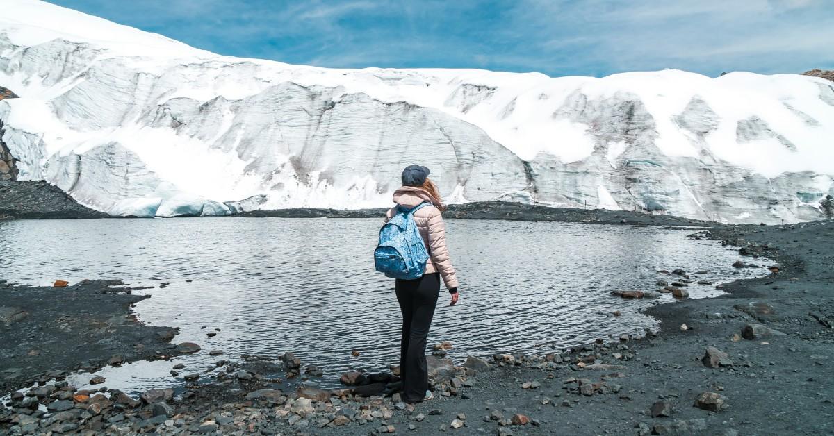 A woman stands in front of the Pastoruri Glacier