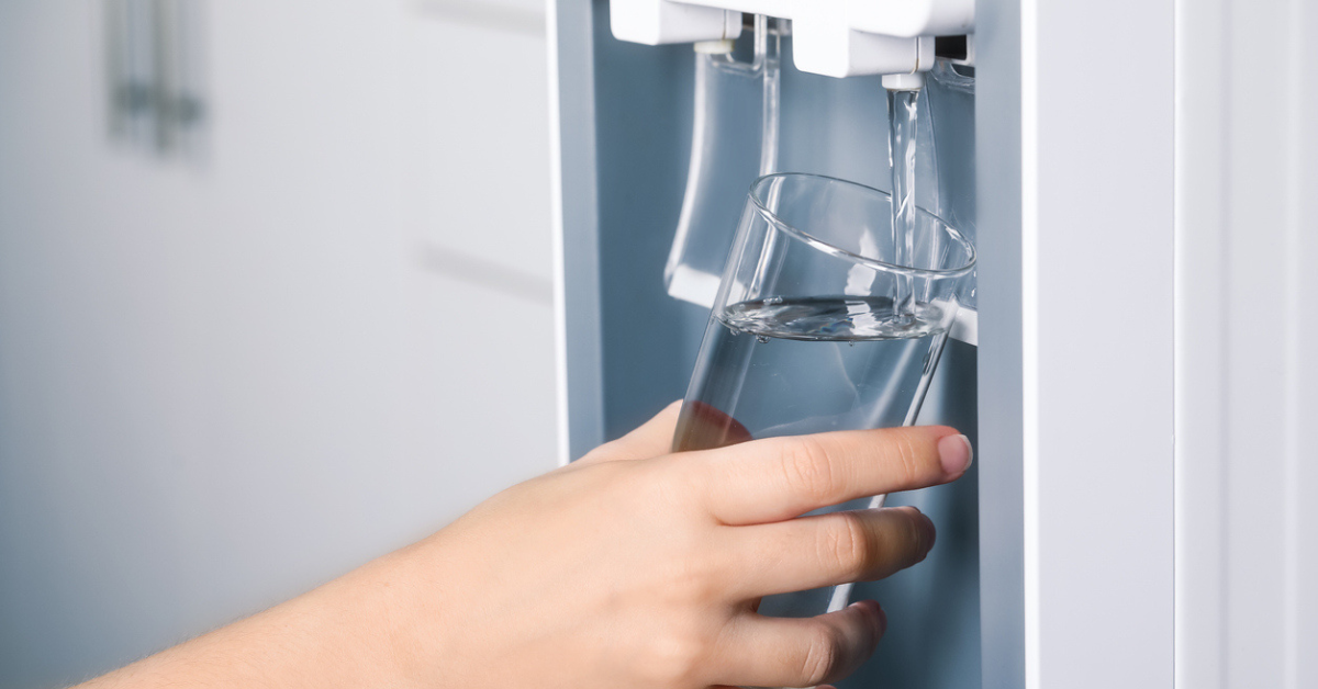 A woman places a glass under her refrigerator to fill it with water 