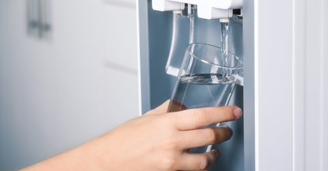 A woman places a glass under her refrigerator to fill it with water